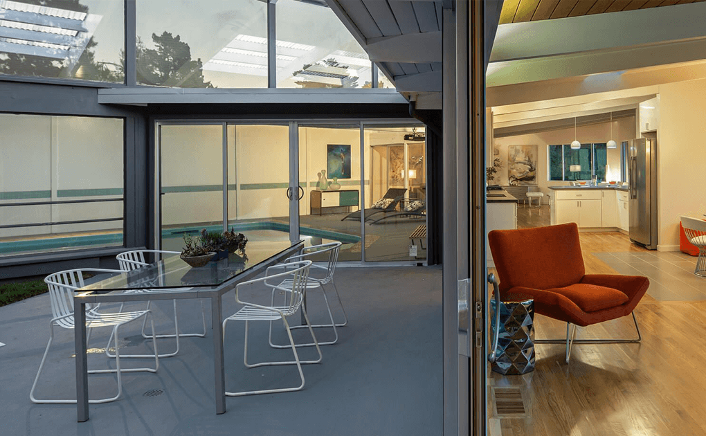 Photo of inside and outside of modern sleek home with big glass windows and sliding doors